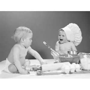 Two Babies With Mixing Bowls and Rolling Pins, One Wearing Chefs Hat 